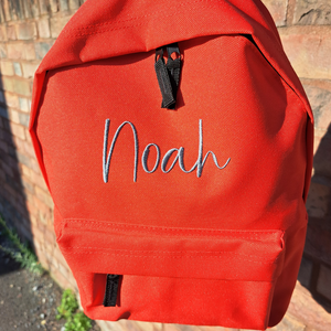 Image of a personalised rucksack for nursery or school which has been personalised with the name Noah in a grey slate embroidery thread. The bag has a main zipped compartment as well as a zipped smaller pocket on the front and two adjustable back straps.