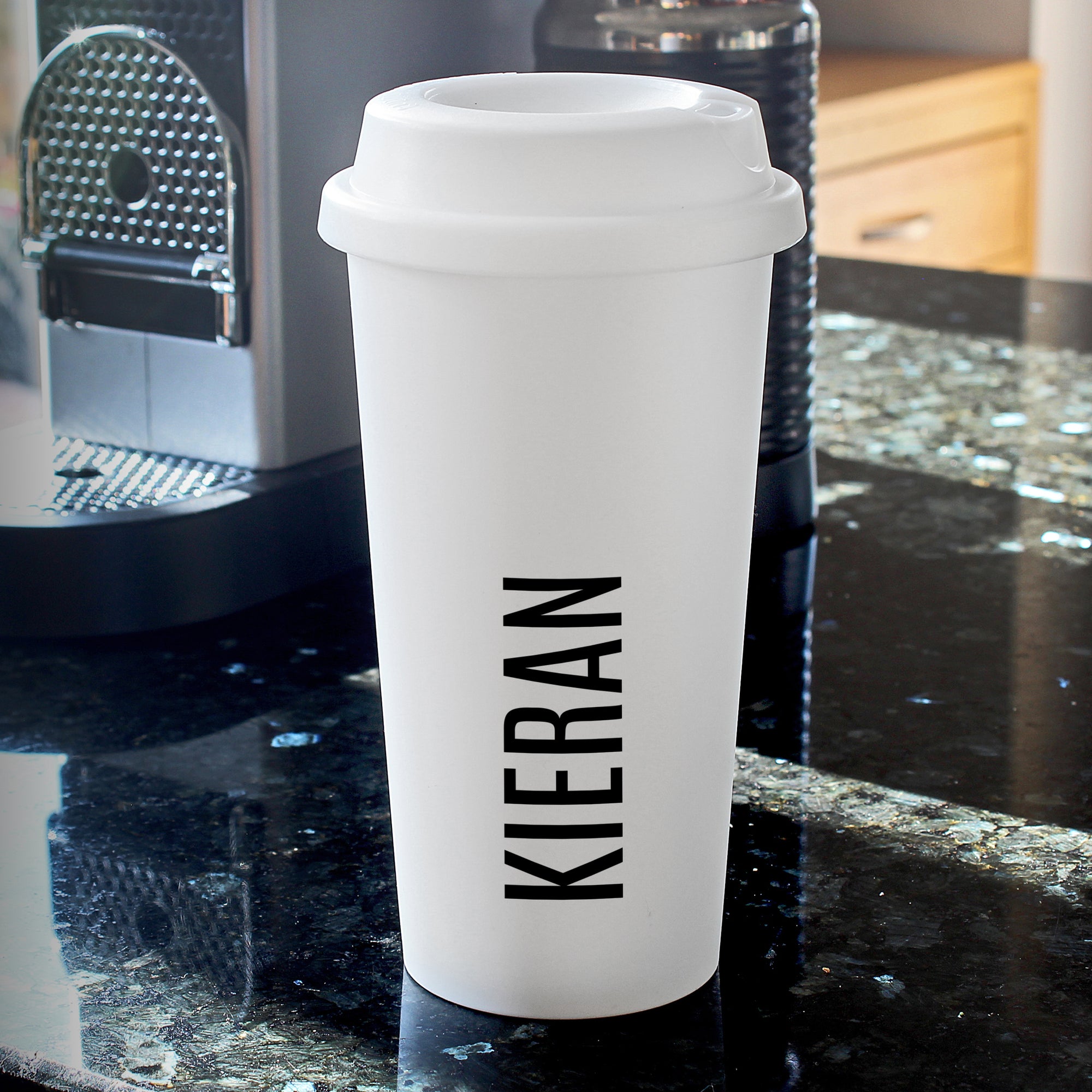 Image of a white plastic travel cup with a white screw on lid that can be personalised with a name of your choice which will be printed in large black capital letters vertically.