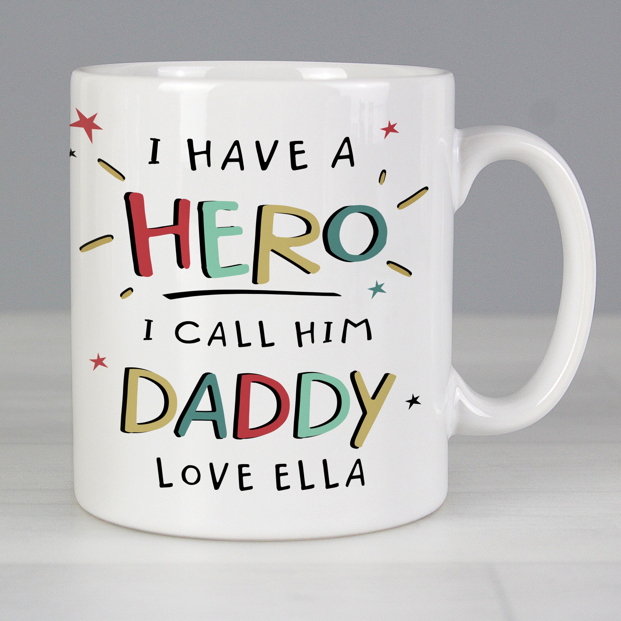 Image of a personalised white ceramic mug for a dad. The front of the mug has 'I have a hero, I call him daddy' on the front that is printed in a large bright uppercase font. Below this there is space to add one line of your own text and the back of the mug can be personalised with your own special message over up to 4 lines which will be printed in a black font.