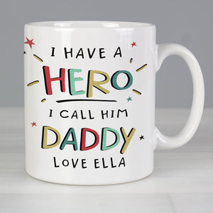 Image of a personalised white ceramic mug for a dad. The front of the mug has 'I have a hero, I call him daddy' on the front that is printed in a large bright uppercase font. Below this there is space to add one line of your own text and the back of the mug can be personalised with your own special message over up to 4 lines which will be printed in a black font.