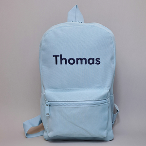 Image of a child's personalised backpack for nursery or school. The backpack shown is powder blue with the name Thomas embroidered on the front in navy. The bag is available in a range of colours and embroidery threads as well as different embroidery fonts.