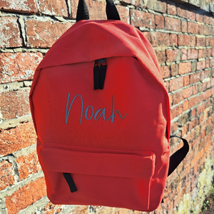 Image of a personalised rucksack for nursery or school which has been personalised with the name Noah in a grey slate embroidery thread. The bag has a main zipped compartment as well as a zipped smaller pocket on the front and two adjustable back straps.