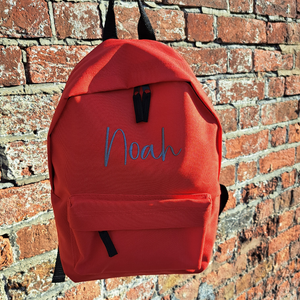 Image of a personalised rucksack for nursery or school which has been personalised with the name Noah in a grey slate embroidery thread. The bag has a main zipped compartment as well as a zipped smaller pocket on the front and two adjustable back straps.