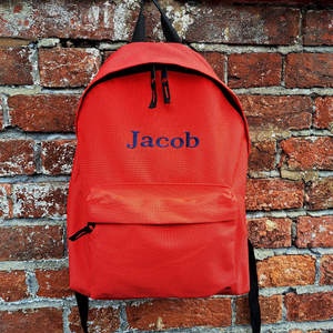 Personalised school rucksack in red which has been embroidered with the name Jacob in a navy blue thread. The bag is available in 13 different colours and in a choice of 6 different fonts.