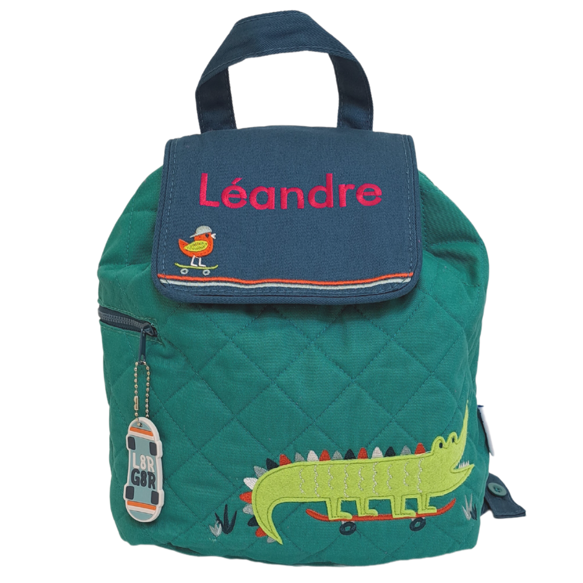 Image of a personalised Stephen Joseph back pack. The back pack has an emerald green main body with a blue closing flap. The bag has an appliqued crocodile on the main body of the bag and a little singing bird on a skateboard on the flap. The bag can be personalised with a name of up to 10 characters which will be embroidered on the flap.