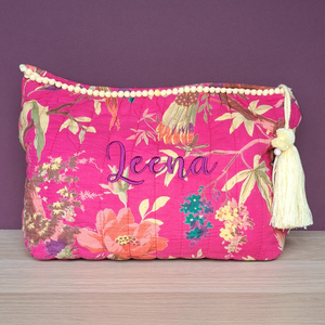 Image of a personalised wash bag. The bag is made from quilted cotton with a vibrant pink design with exotic birds and flowers. The bag is lined with white water resistant fabric and has a lemon coloured tassle on the zip pull as well as lemon pom pom decorations along the top.