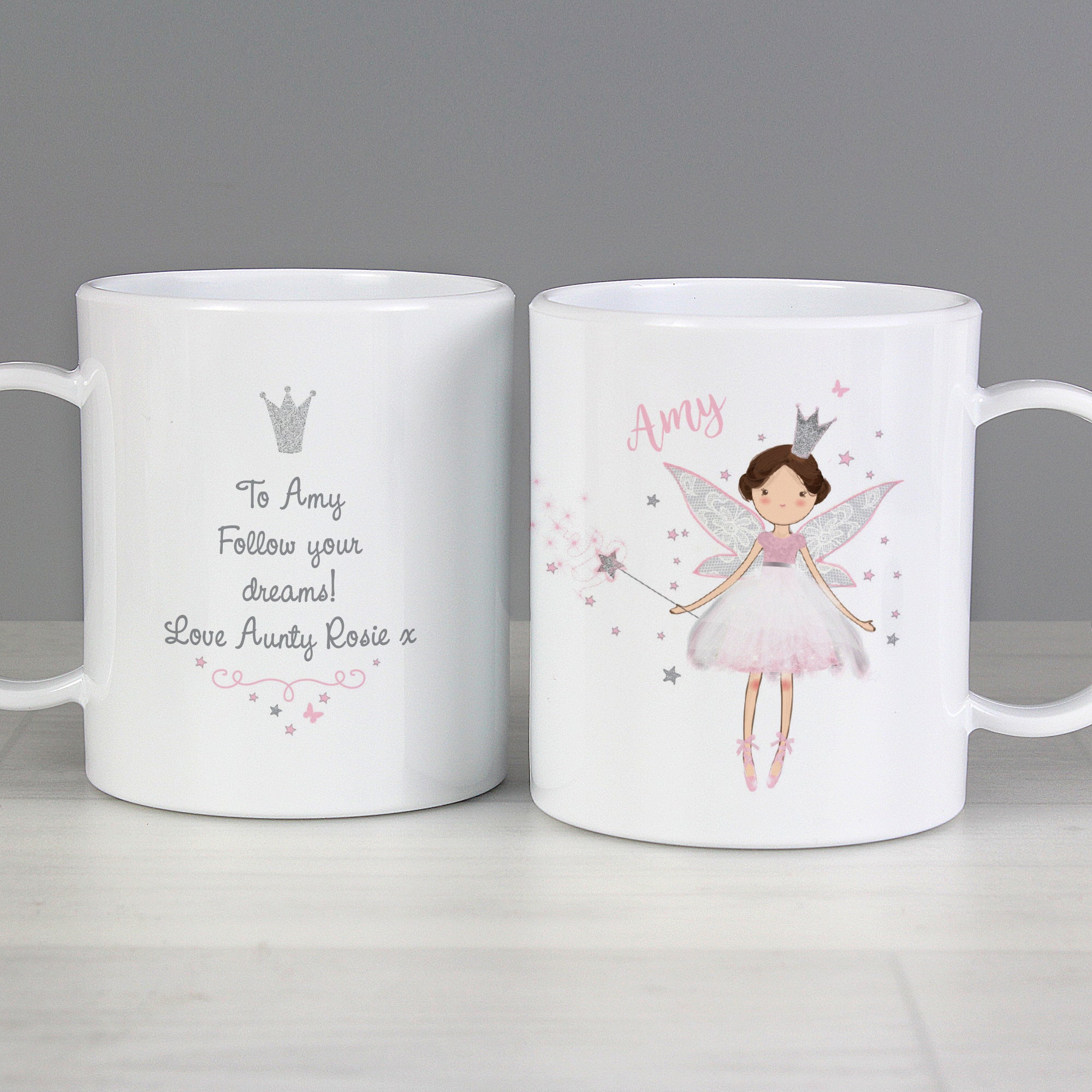 Image of a plastic BPA free childs personalised cup. The cup is white and has an image of a fairy at the front wearing a pink dress and with a silver crown and holding a wand. The plate can be personalised with a name of your choice which will be printed just above the fairy on the left side in a pink cursive font.  The back of the cup features a silver glitter crown and beneath it you can add your own message over 4 lines which will be printed in a delicate black font.