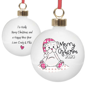 Personalised white ceramic round Christmas bauble which features an image of a hand-drawn teddy bear wearing a Christmas hat and the wording 'Merry Christmas' in a hand-written font.  You can add a year to the front of the bauble which will be printed below the 'Merry Christmas' and on the back, you can add your own special message over up to 4 lines. The bauble comes with a ribbon ready to hang it on a tree.
