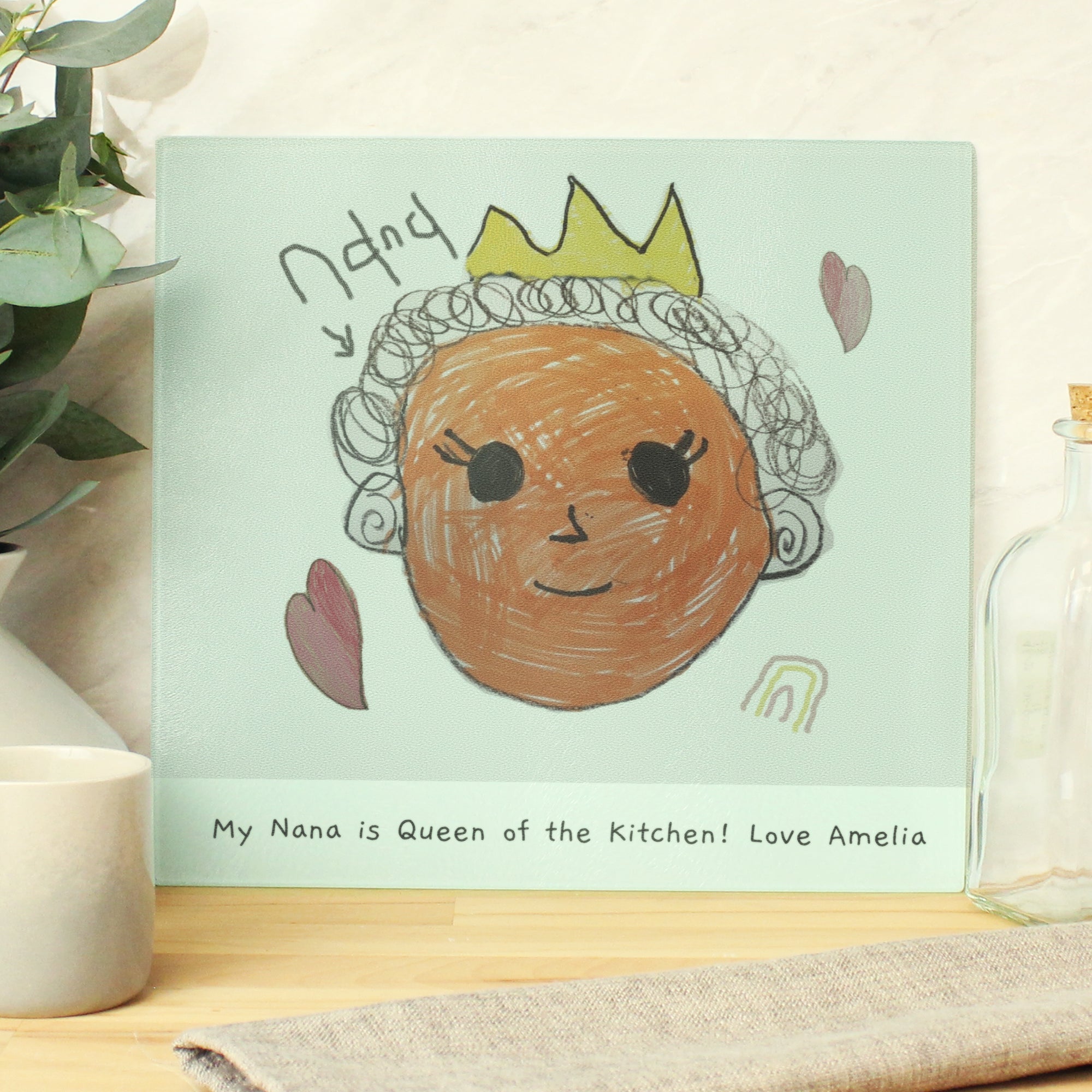 Image of a glass chopping board that can be personalised by having your child's own drawing printed on it and underneath the drawing, you can choose to add your own message or text which will be printed in a black handwritten style font.