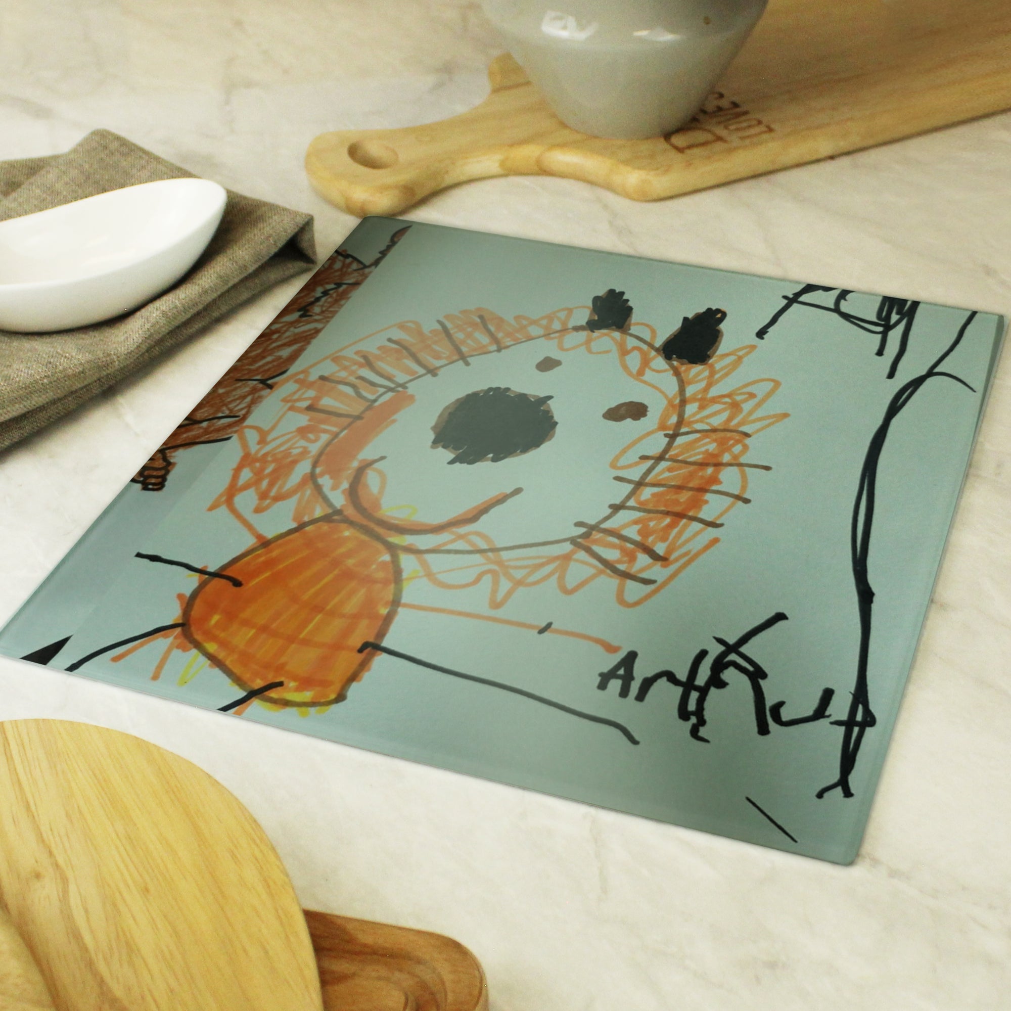 Image of a glass chopping board that can be personalised by having your child's own drawing printed on it and underneath the drawing, you can choose to add your own message or text which will be printed in a black handwritten style font.