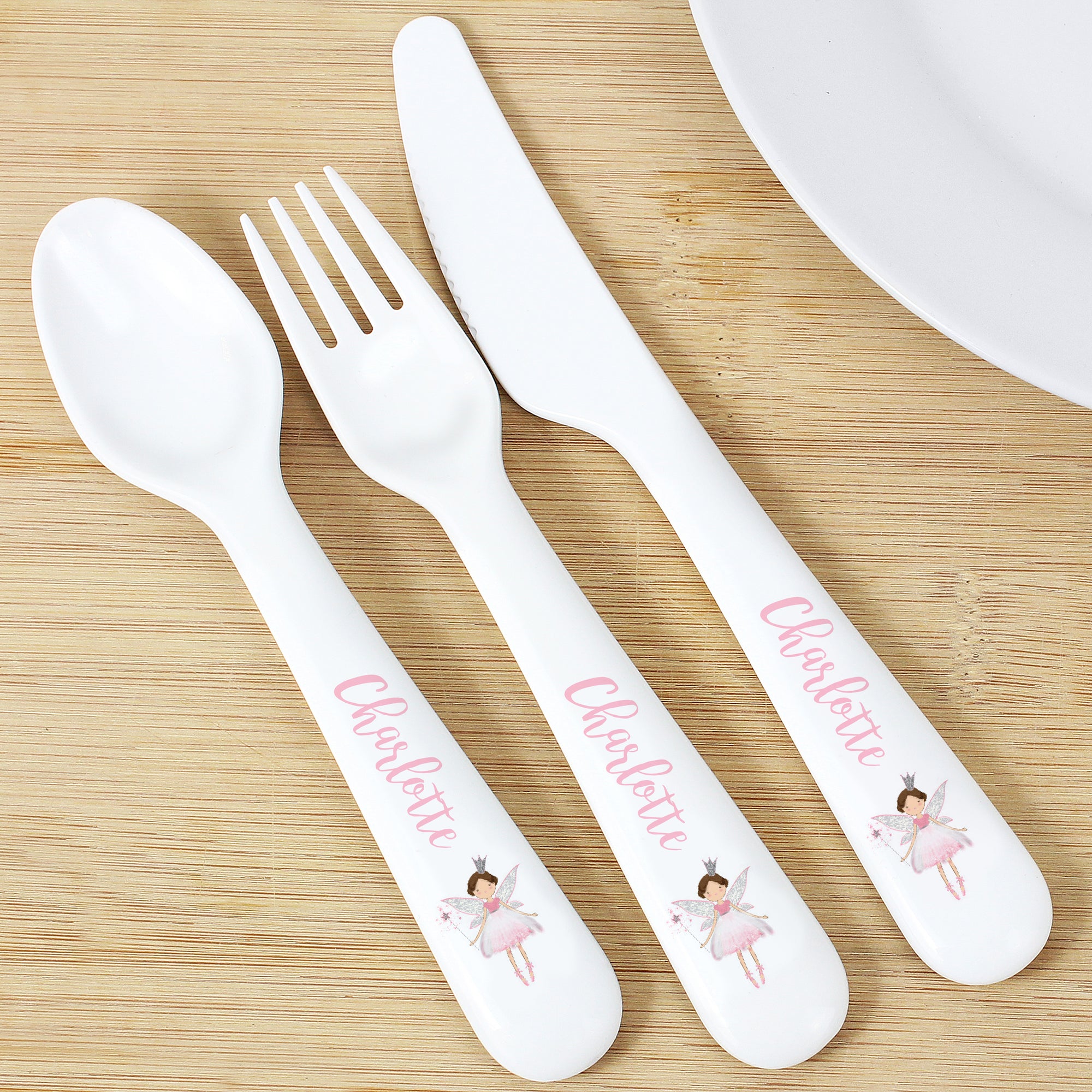 Image of a plastic BPA free child's cutlery set. The cutlery set comprises of a spoon, fork and knife that are white and there is an image of a fairy at the end of the handle. The handles can also be personalised with a name of your choice of up to 12 characters which will be printed in a pink cursive font.