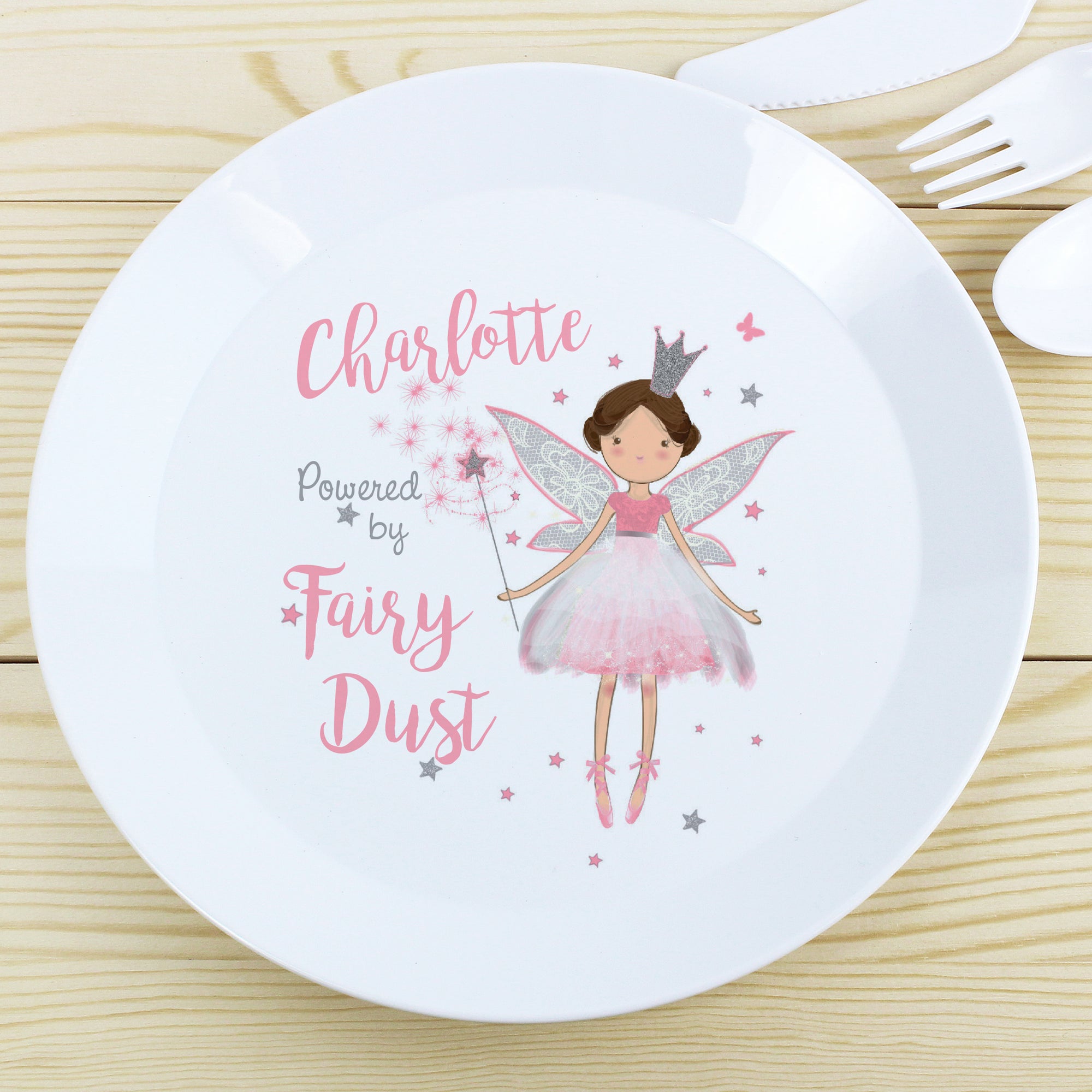 Image of a white plastic BPA free childs personalised plate. The plate is white with a rim and in the centre of the plate is a cartoon drawing of a fairy holding a wand and the text 'Powered by Fairy Dust'. The plate can be personalised with a name up to 12 characters in a pink font. The plate is part of a set and comes with a cup and cutlery set in the same theme.