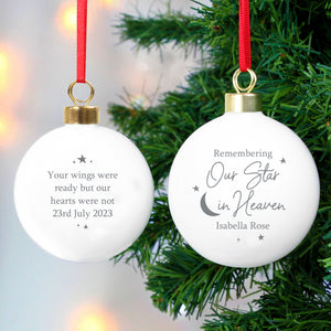 Image of the front and back of a personalised memorial Christmas bauble. The bauble is white and the front features the wording ‘Remembering Our Star in Heaven’ in a great font which is a fixed part of the design and you can add a name of your choice underneath. You can add your own message to the back of the bauble which will be printed in a grey font with some stars around the writing.