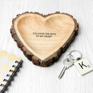 Image of a hand-carved heart-shaped wooden bowl that has a rustic natural bark edging. The bowl can be personalised with your own message which will be engraved in an upper case font.