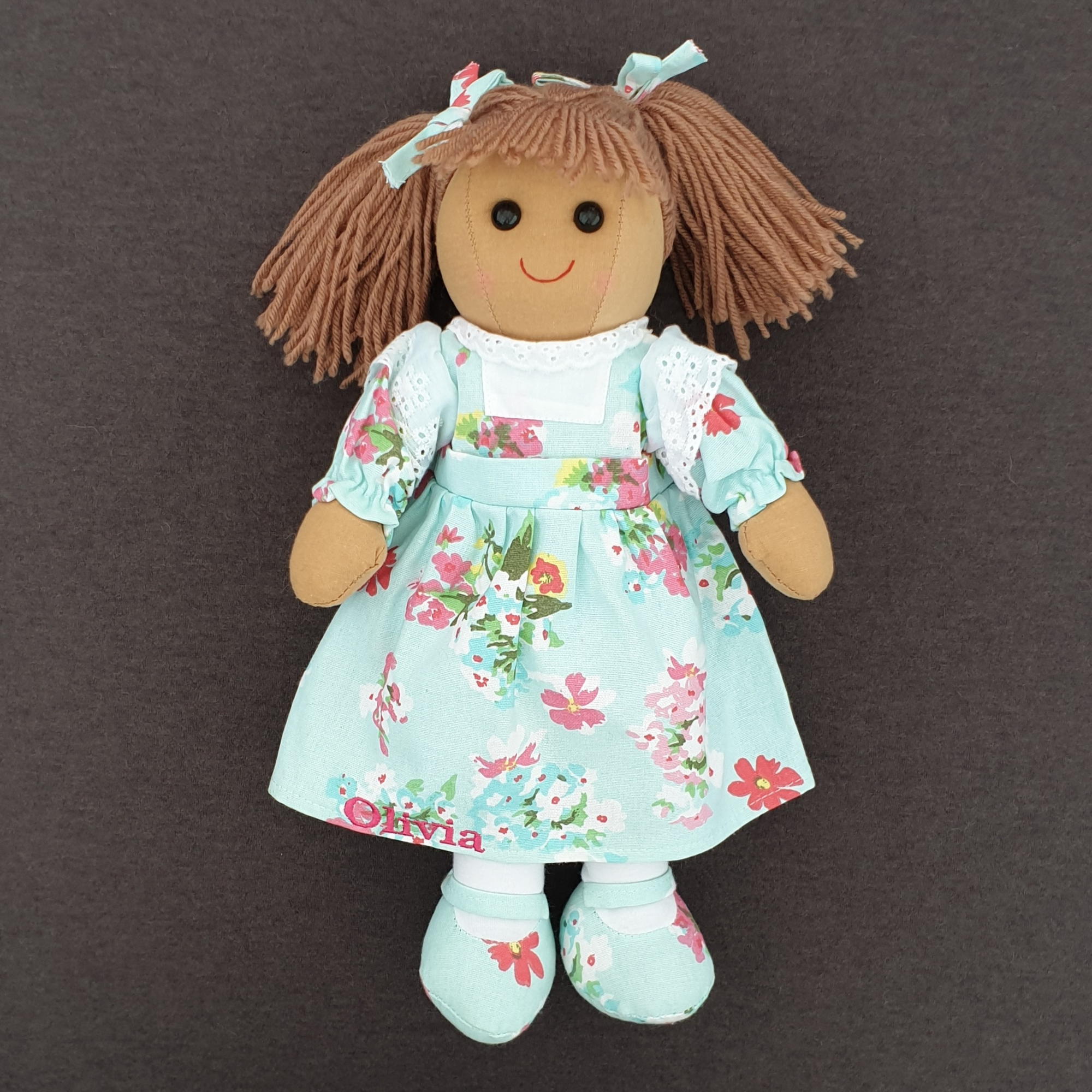 Personalised rag doll wearing a blue floral dress that can be personalised with a name of up to 10 characters. Underneath her dress she is wearing white pantaloons.