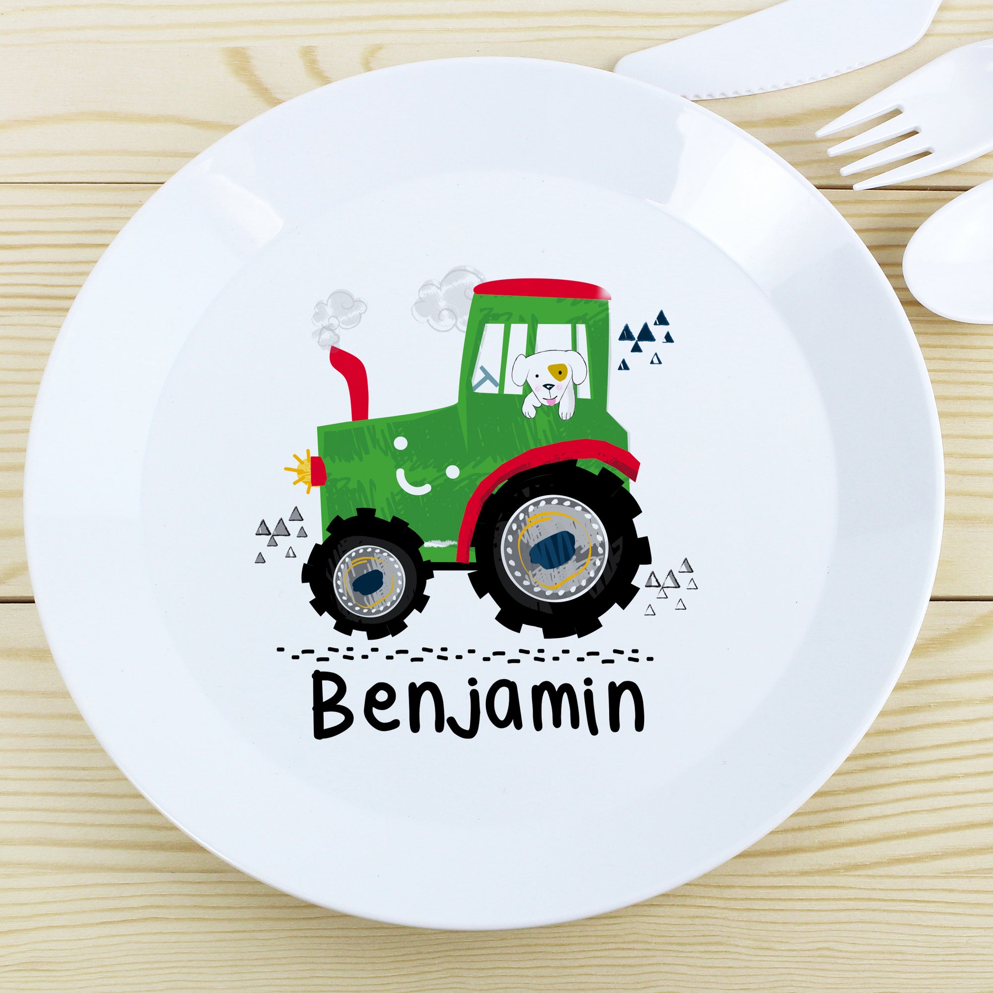 Image of a white plastic BPA free childs personalised plate. The plate is white with a rim and in the centre of the plate is a cartoon drawing of a green tractor with a dog in the cab. Beneath the image of the tractor the plate can be personalised with a name up to 12 characters in a black font. The plate is part of a set and comes with a cup and cutlery set in the same theme.