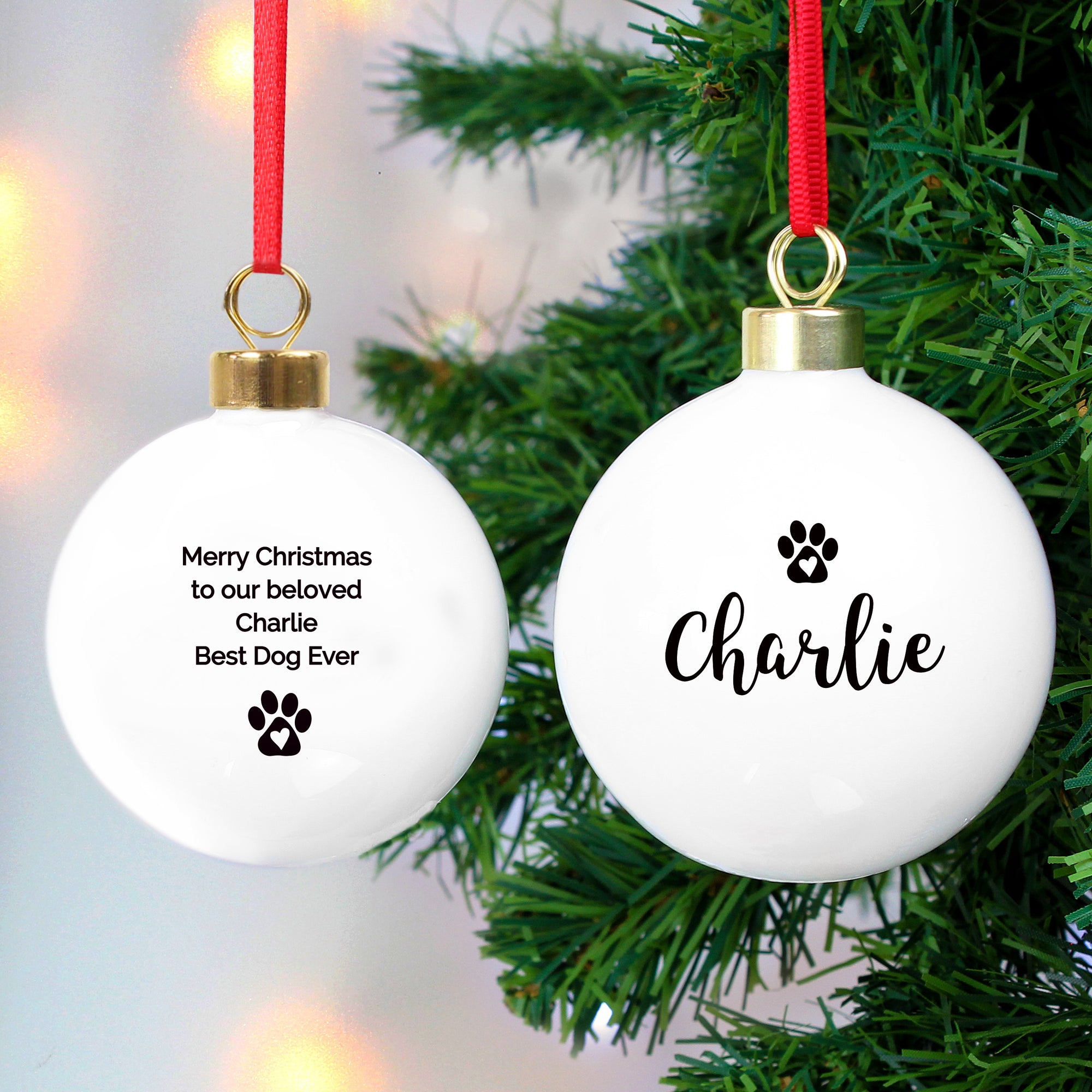 Personalised Christmas bauble for a pet. This white ceramic Christmas tree bauble can be personalised on the front with a name of up to 12 characters which will be printed in a black modern italic font and there is a black paw print with a white heart inside it above the name. The rear of the bauble can be personalised with your own mesage over up to 4 lines of 20 characters per line which will be printed in black. There is also a black paw print with a white heart inside it printed underneath the message.