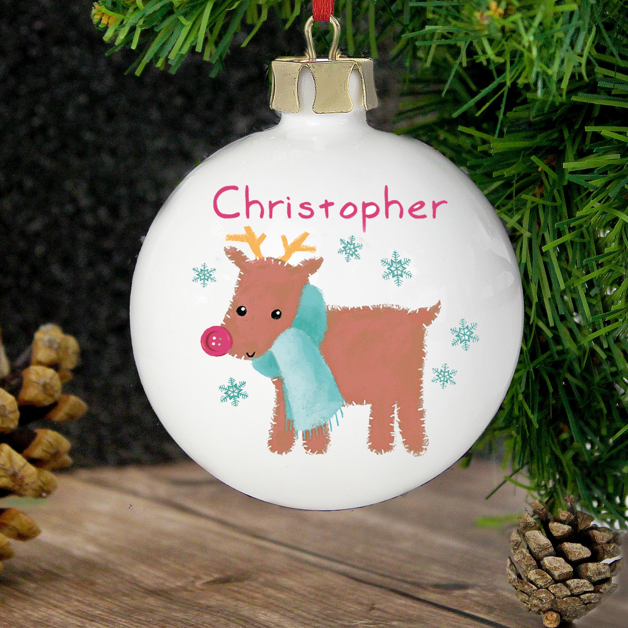 personalised white ceramic round Christmas bauble featuring an image of a hand-drawn reindeer wearing a scarf.  The front of the bauble can be personalised with a name of your choice which will feature above the reindeer and on the back, you can put your own special message over 4 lines.