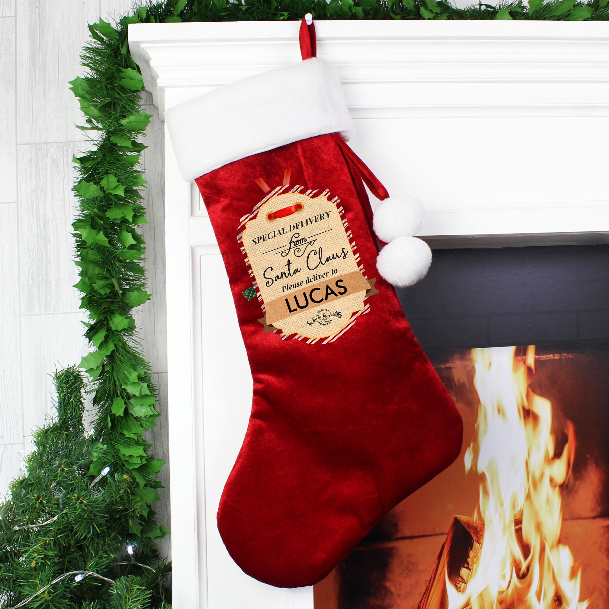 Personalised red plush Christmas stocking with a white fur trim.  The front of the stocking is printed with 'Special delivery from Santa Claus Please deliver to' and then a name of your choice can be added of up to 12 characters.  The stocking has a small loop so it can be hung from a hoop as well as two white fur pom poms hanging from one side.