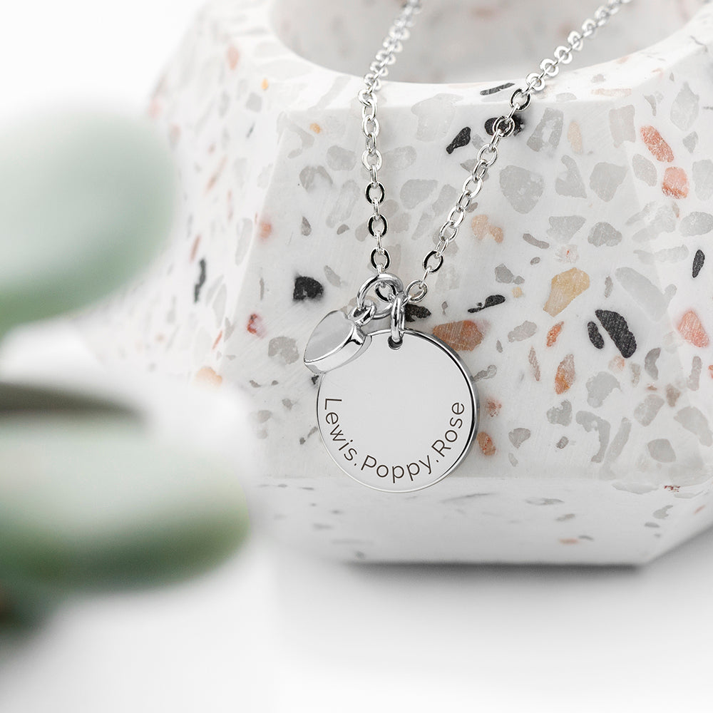Personalised silver plated necklace with a disc that can be engraved with a name or message of your choice and a small heart charm next to it. The necklace comes with a silver plated necklace.