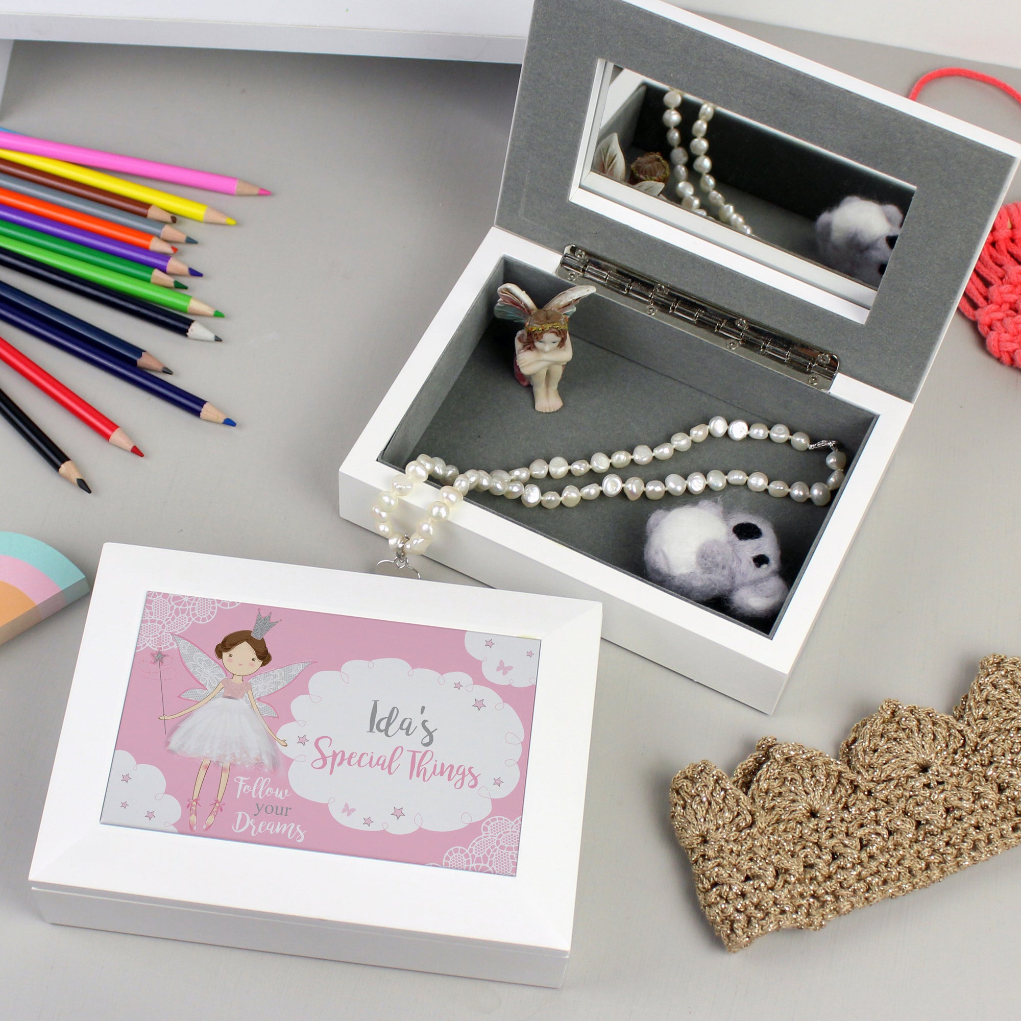 Image of a child's white jewellery box. The outside of the lid has an image of a fairy holding a wand and a cloud which can be personalised with your own text. The inside of the box is lined with a grey fabric and there is a model of a fairy inside the box as well as a mirror in the lid.