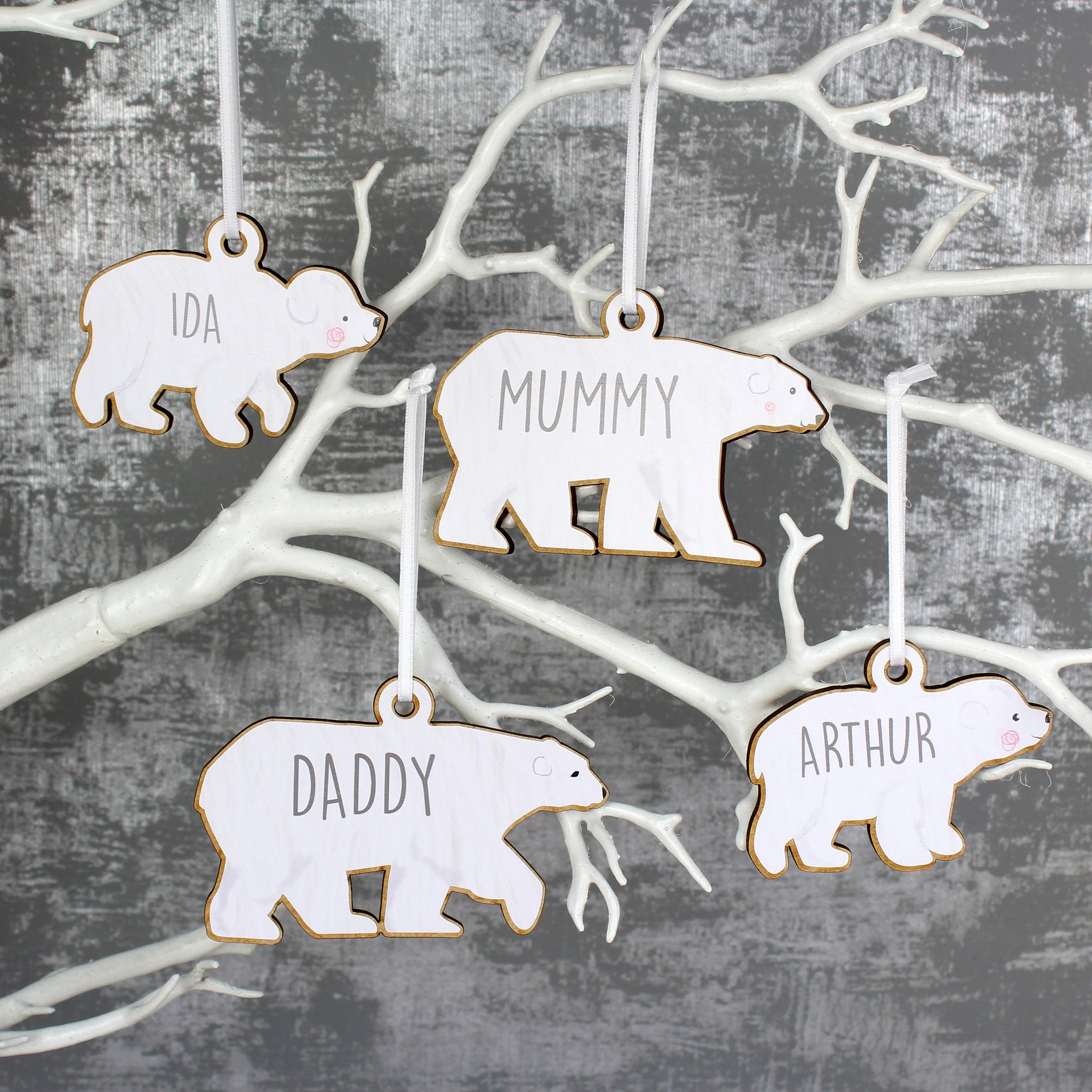 Personalised family set of four wooden polar bear decorations with two adults and two baby bears. Each bear is painted white and can be personalised with a name of up to 12 characters which will be printed on each bear in a modern grey uppercase font.