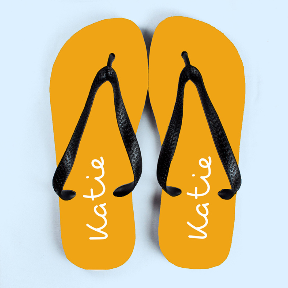 Image of a pair of yellow flip flops that have been personalised with a name of your choice of up to 12 characters which will be printed in white. The flip flops have a black strap.