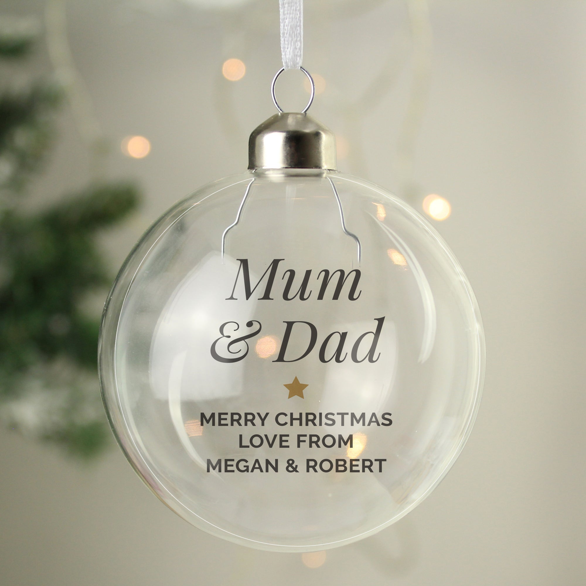 Image of a clear glass Christmas bauble that can be personalised with your own message over up to 5 lines.  The first two lines are printed in a large italic font and remaining lines will be printed in a smaller uppercase font.  Lines 2 and 3 are separated by a small gold star.