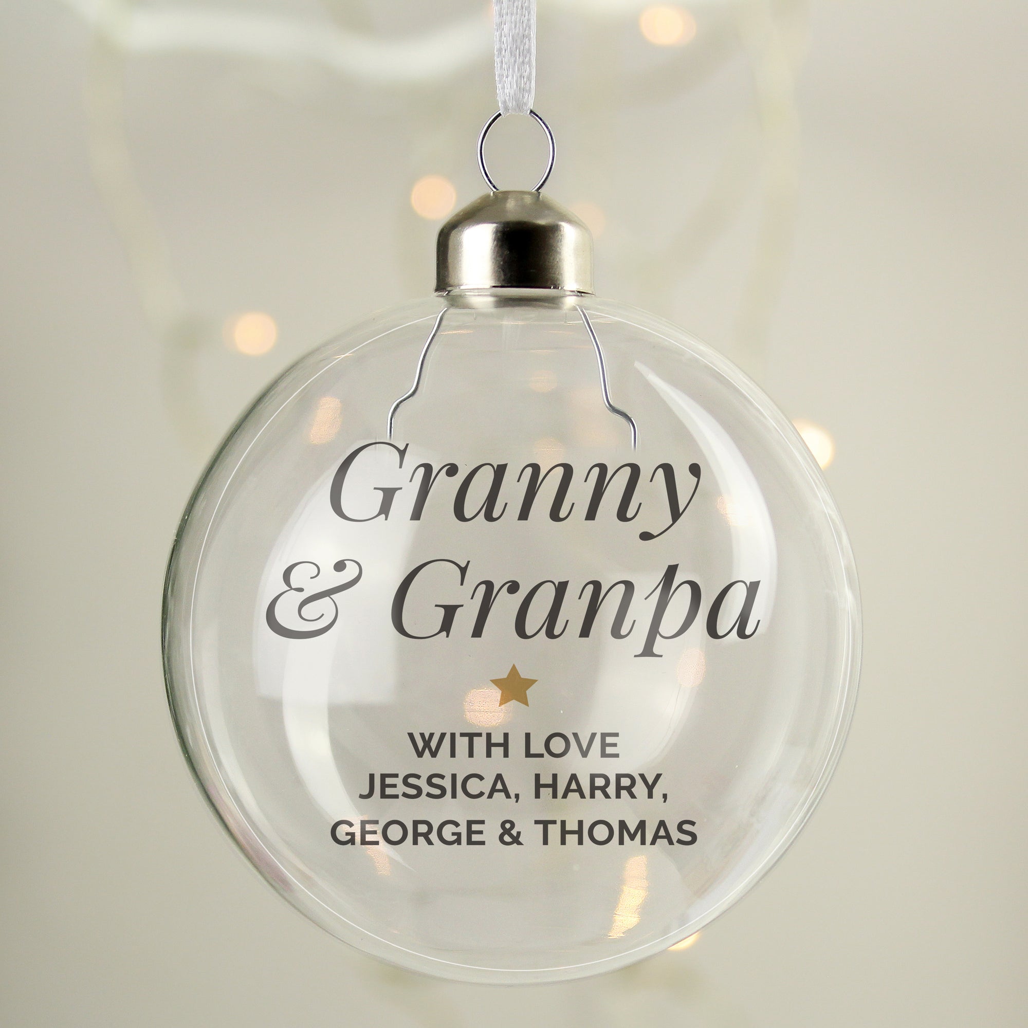 Image of a clear glass Christmas bauble that can be personalised with your own message over up to 5 lines.  The first two lines are printed in a large italic font and remaining lines will be printed in a smaller uppercase font.  Lines 2 and 3 are separated by a small gold star.