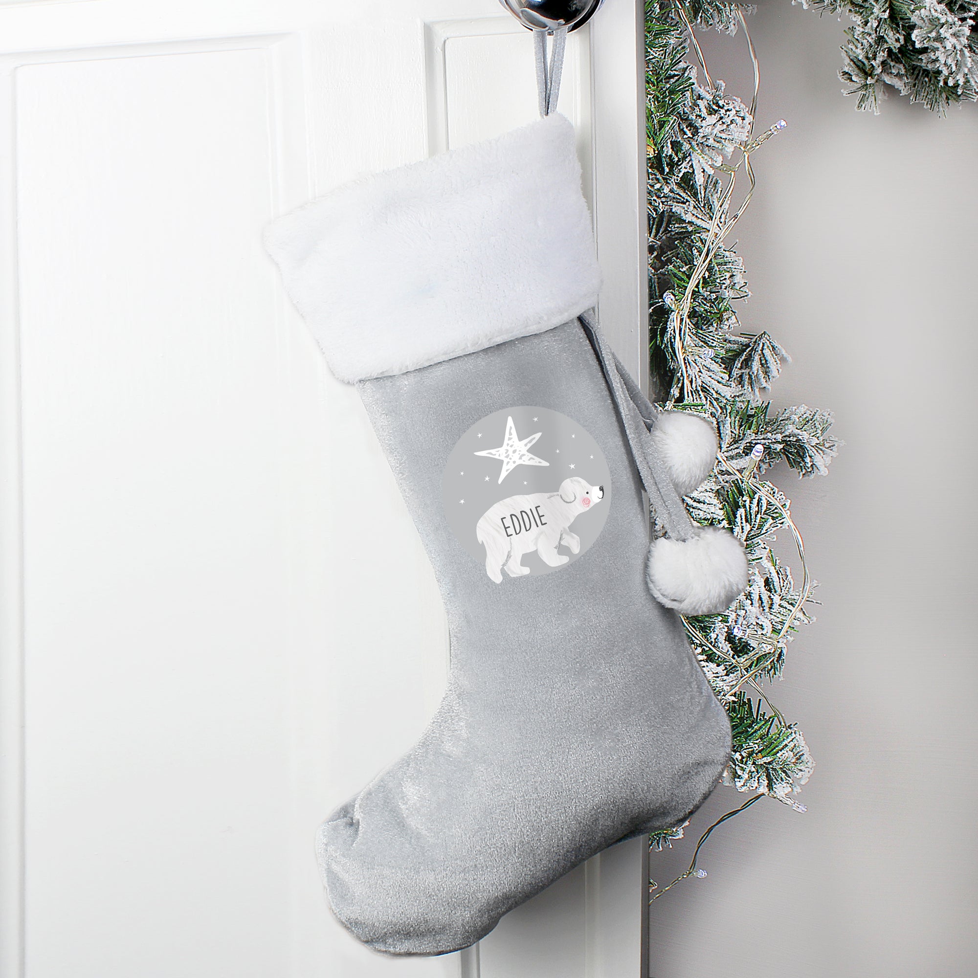 Personalised grey velvet Christmas stocking with a plush white trim. The front of the stocking features an illustration of a hand-drawn baby polar bear with a star above it and the stocking can be personalised with a name of your choice which will be printed in a black modern uppercase font inside the image of the bear.