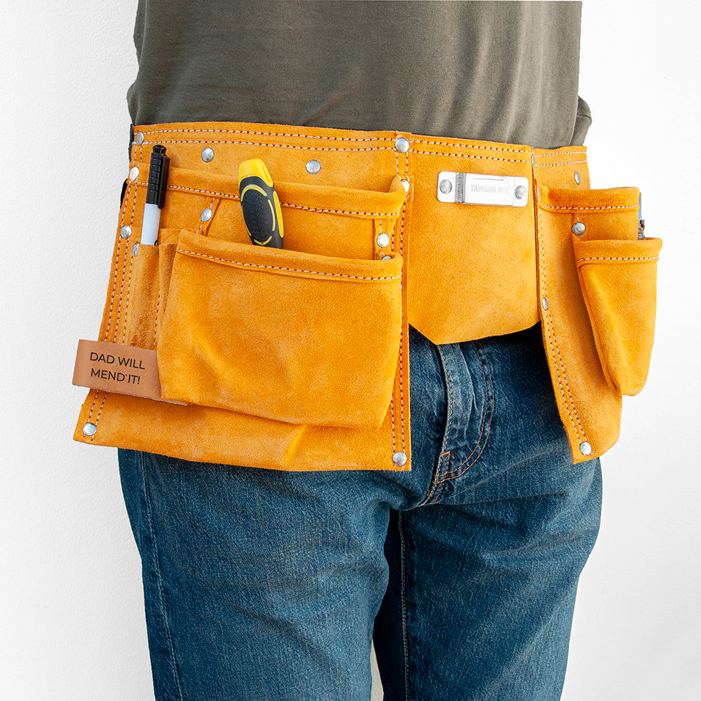 Image of a tool belt made from heavy duty tan leather. The belt has 11 pockets for carrying essential tools, nails, screws, pens, scissors, tape measure, etc necessary for DIY, construction, florists or artists. The belt has a fully adjustable nylon webbed belt to fit around an adult waist. The tool belt has a leather tag which can be personalised with a message of your choice.