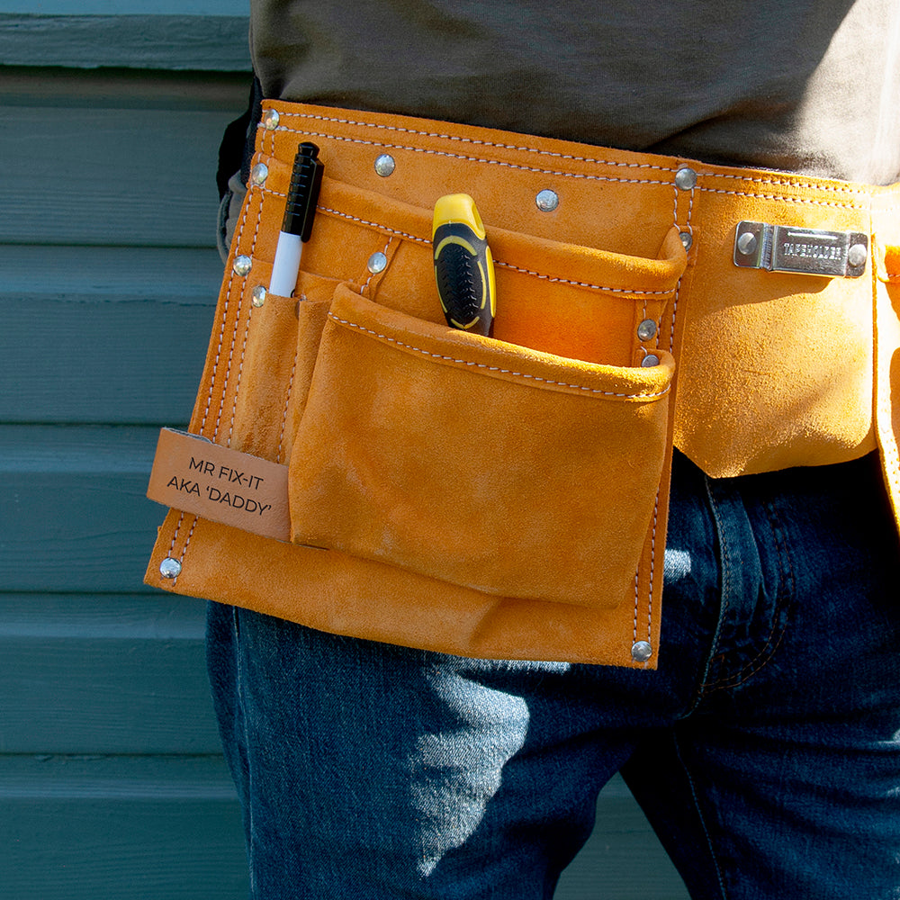 Image of a tool belt made from heavy duty tan leather. The belt has 11 pockets for carrying essential tools, nails, screws, pens, scissors, tape measure, etc necessary for DIY, construction, florists or artists. The belt has a fully adjustable nylon webbed belt to fit around an adult waist. The tool belt has a leather tag which can be personalised with a message of your choice.