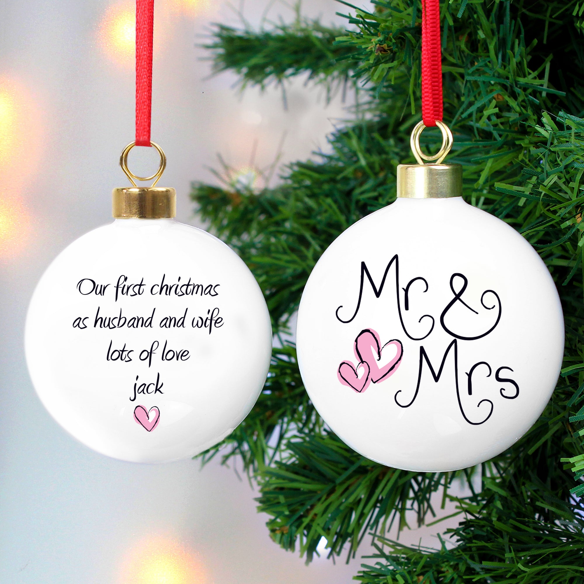 Personalised Mr & Mrs Christmas decoration for a married couple. This round white ceramic Christmas bauble has 'Mr & Mrs' printed on the front in a hand-written style font along with two pink love hearts. The back of the bauble can be personalised with your own special message and has another pink heart printed below the text.