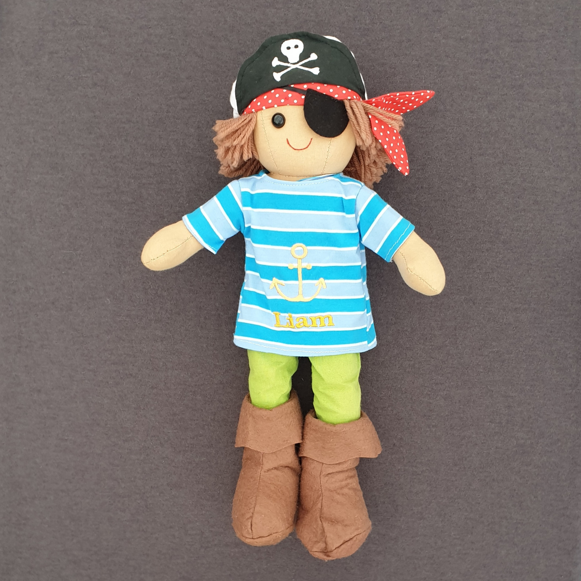 Personalised pirate rag doll. Our pirate rag doll is made from cotton and suitable from birth. He is wearing a blue striped t-shirt which can be personalised with a name of your choice. He also has a pirate hat, eye patch and soft brown boots.