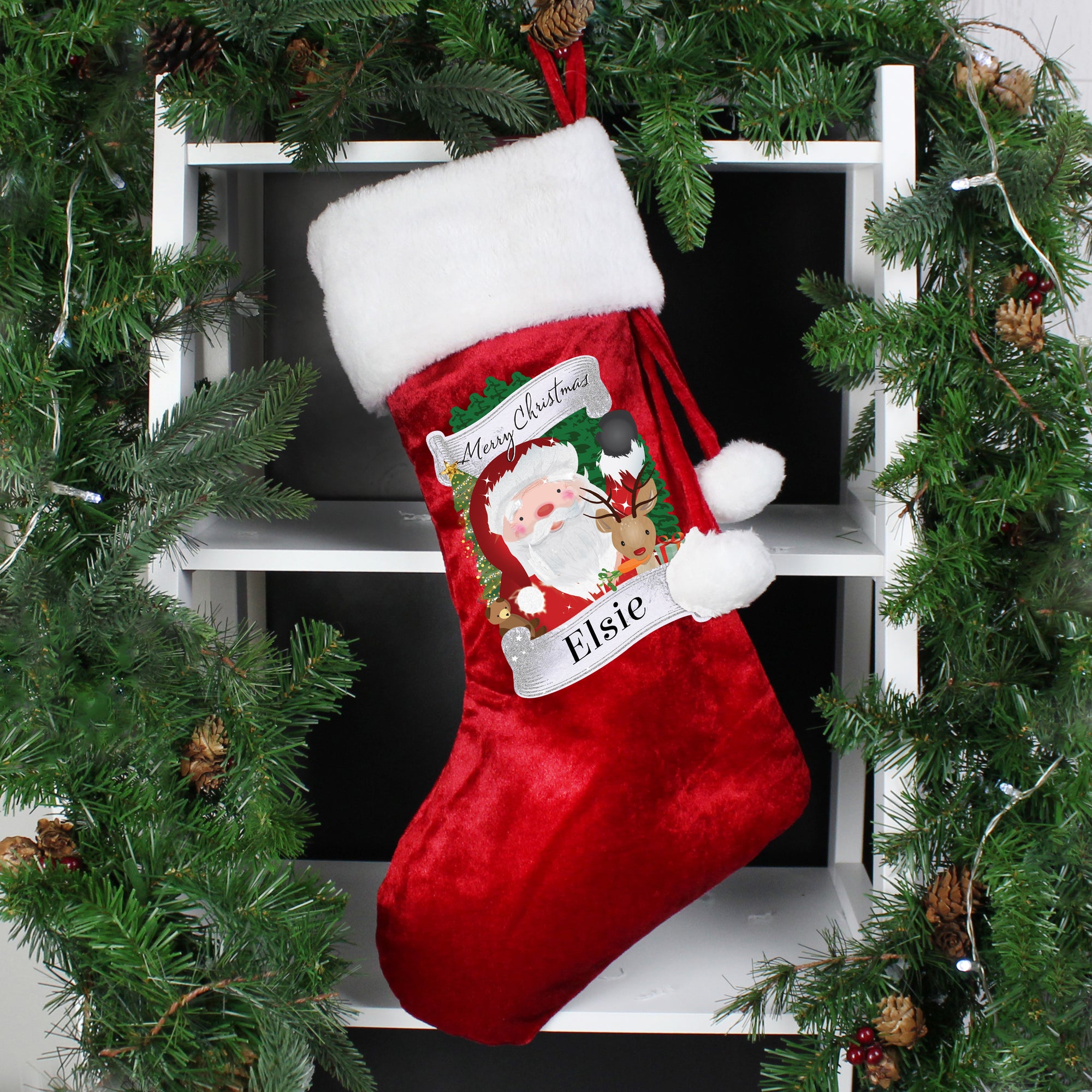 Personalised soft red velvet Christmas stocking featuring an cartoon illustration of Santa and the wording Merry Christmas. There is a white fur cuff on the top of the stocking along with a hoop to hang it from. The front of the stocking can be personalised with a name of your choice of up to 12 characters which will be printed just below the illustration of Santa in a black font.