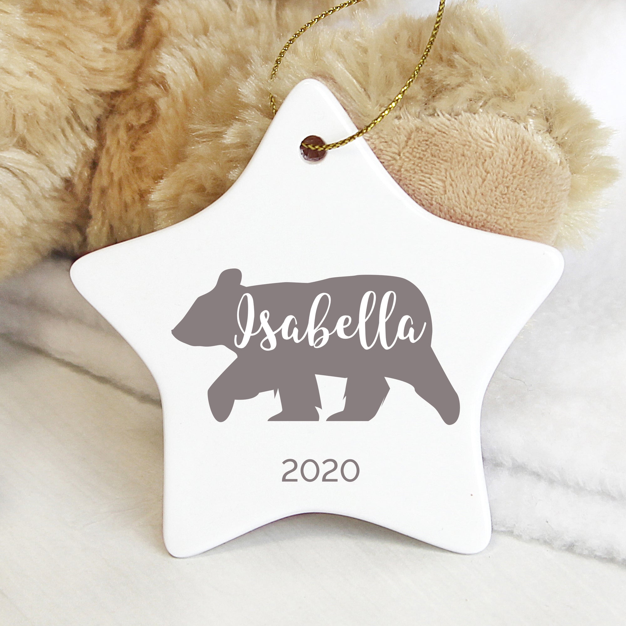 Personalised white ceramic star shaped Christmas tree decoration which features a grey polar bear on the front.  The decoration can be personalised with a name of your choice of up to 12 characters which will be printed in white in a modern hand drawn style font within the polar bear and you have the option to add a date which will be printed below the star, of up to 20 characters.