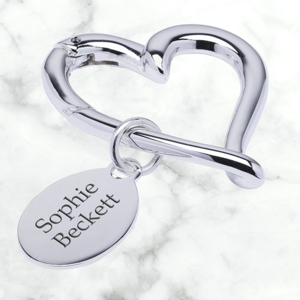 Image of a personalised silver coloured open heart keyring with a label that can be engraved with a name of your choice