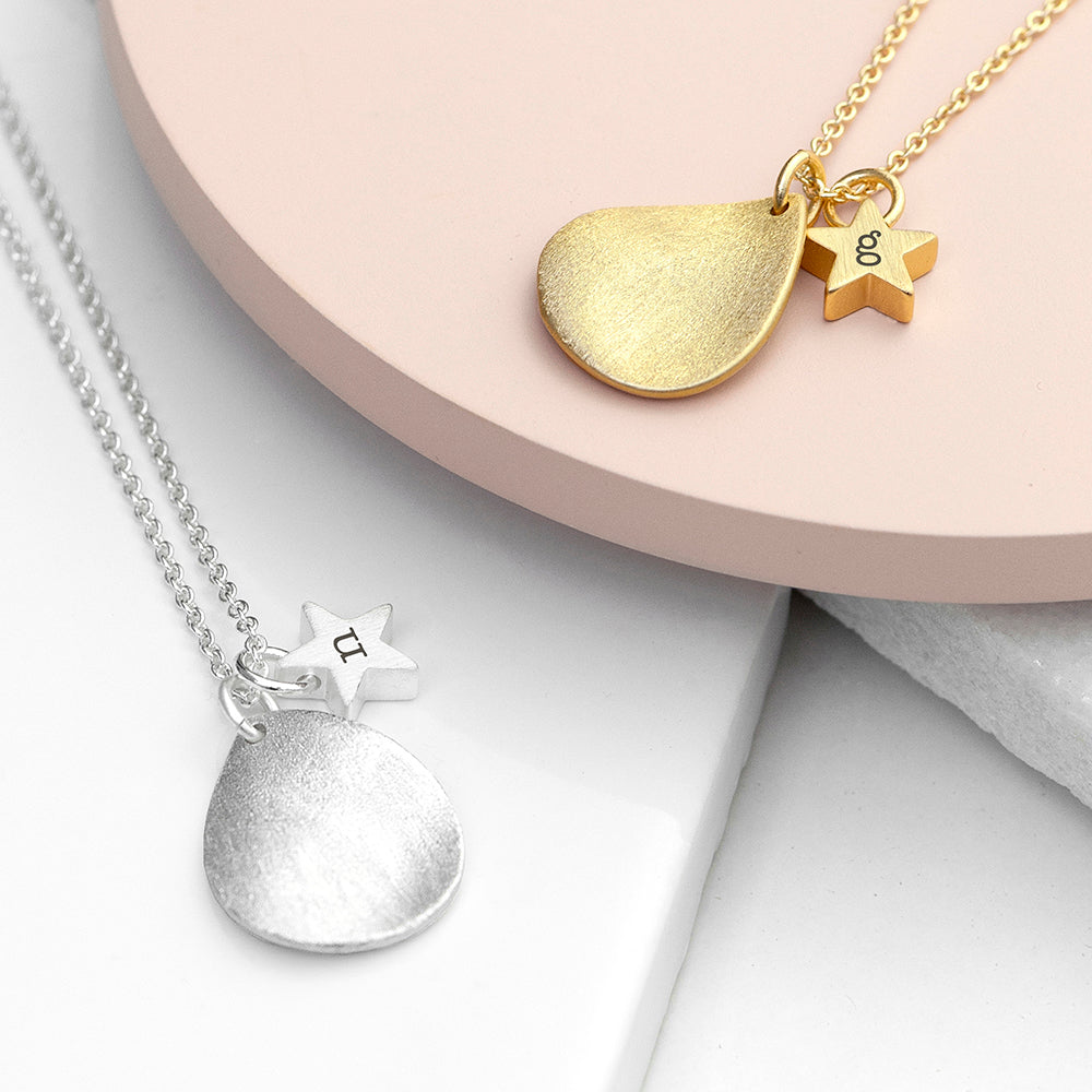An image of two personalised necklaces, one is plated in sterling silver and the other in 18ct gold. The necklaces have a matt finished drop shape on them and a small matt finish star which can be engraved with an initial.
