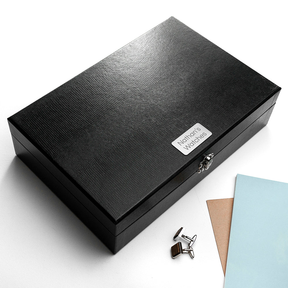 Image of a black box with 12 internal compartments for holding cufflinks and storage for up to 6 watches. The box is made from black PU leather and fastens shut with a silver coloured clasp. The lid of the box has a silver coloured plaque that can be engraved with your own text over 2 lines of up to 10 characters per line in your choice of two fonts.