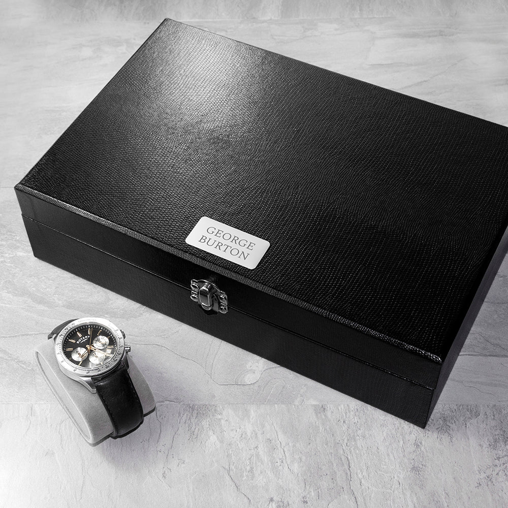 Image of a black box with 12 internal compartments for holding cufflinks and storage for up to 6 watches. The box is made from black PU leather and fastens shut with a silver coloured clasp. The lid of the box has a silver coloured plaque that can be engraved with your own text over 2 lines of up to 10 characters per line in your choice of two fonts.