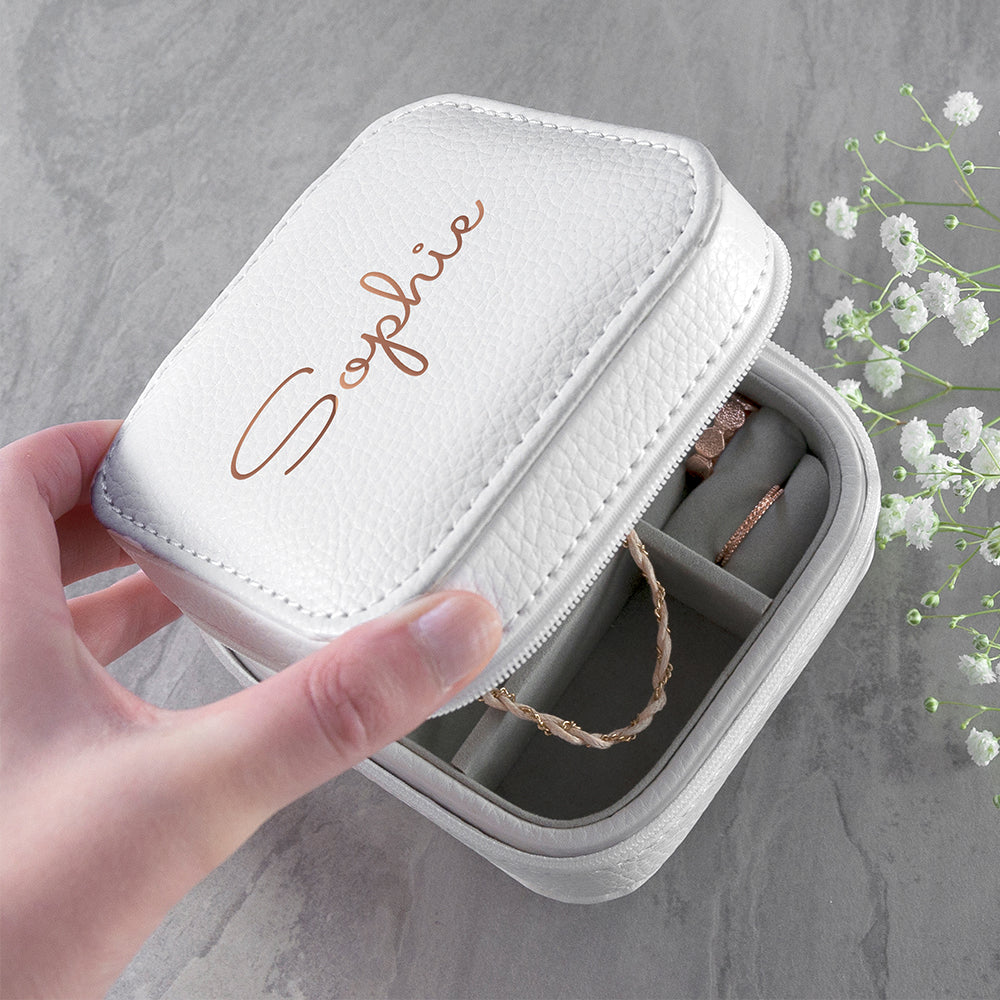 Image of a white leather square travel jewellery case that can be personalised with a name of your choice of up to 15 characters on the lid in a choice of colours and 3 different fonts. The case closes securely with a white zip and internally has flock lined compartments for storing jewellery.