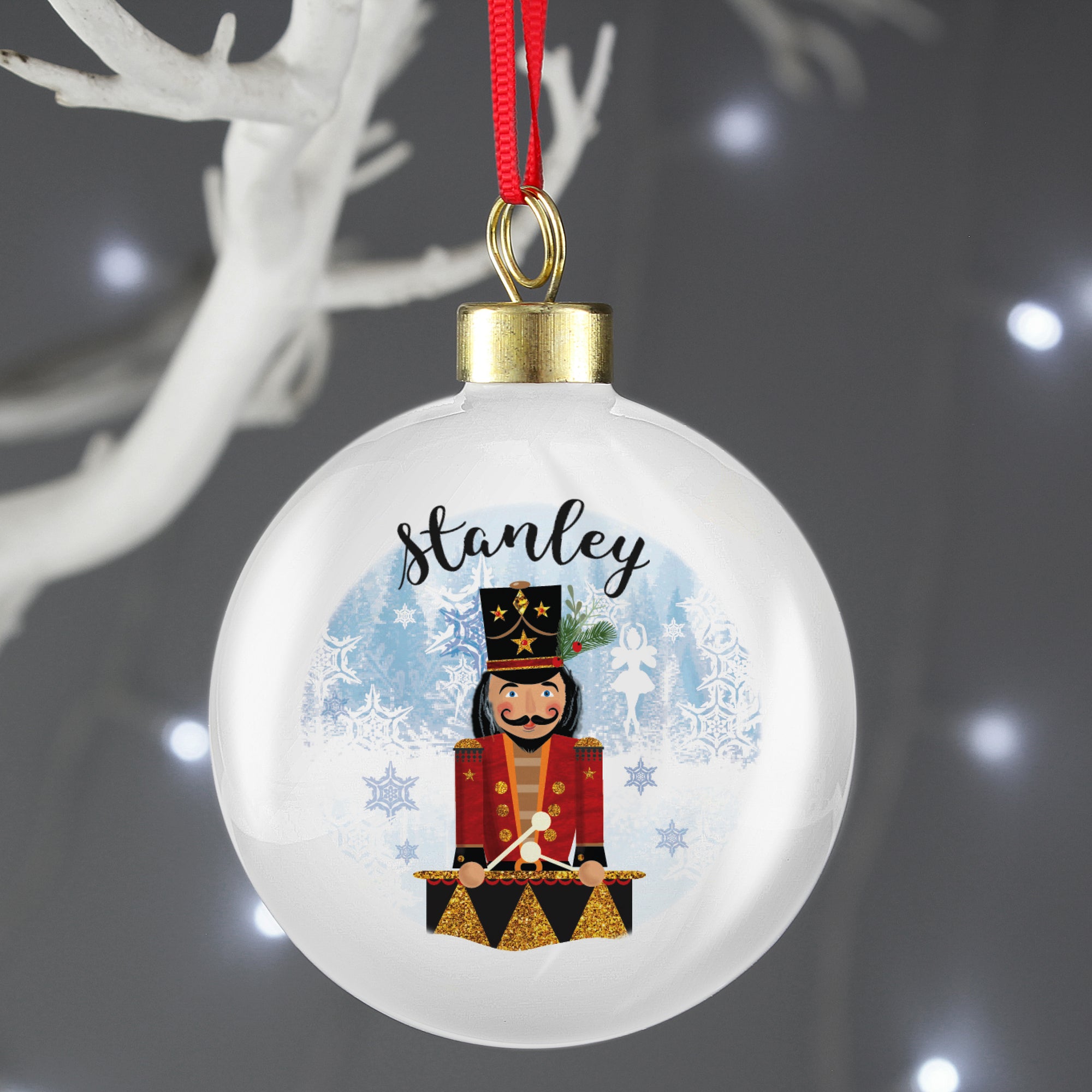 Personalised Christmas bauble featuring an image of a hand drawn wooden nutcracker toy with a drum. A name of your choice will be printed above the image in a black modern cursive font. The rear of the bauble can be personalised with your own special message over up to 4 lines. The bauble comes ready to hang with a ribbon.